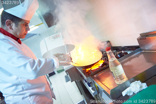 Image of chef in hotel kitchen prepare food with fire