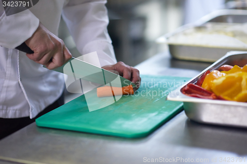 Image of chef in hotel kitchen  slice  vegetables with knife