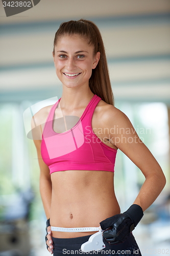 Image of young fit woman measuring belly