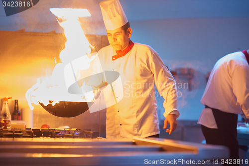 Image of chef in hotel kitchen prepare food with fire