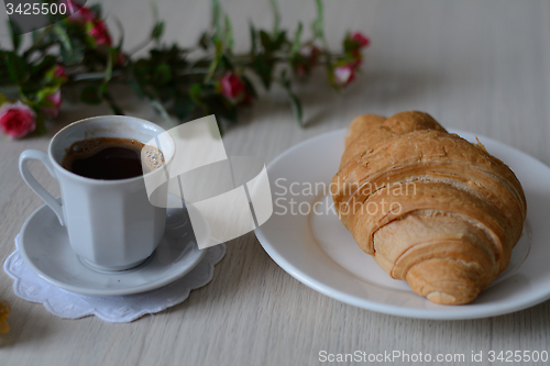 Image of cup of strong coffee and a croixant 