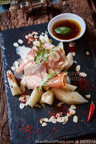 Image of salad of fresh melon with thin slices prosciutto