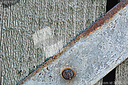 Image of Closeup head of big metal screw on wooden plate