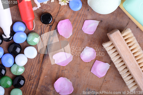 Image of comb, sea salt, spa stones and flower petals on wooden table, closeup