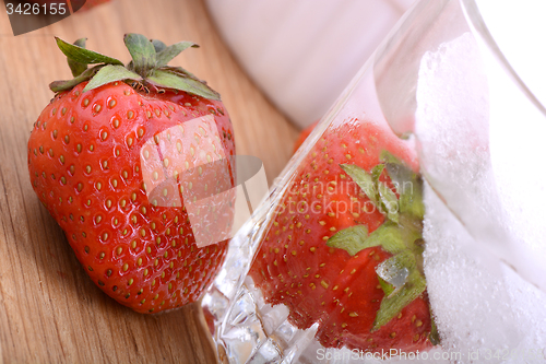 Image of Strawberry on wooden plate and strawberry frozen with ice in cup