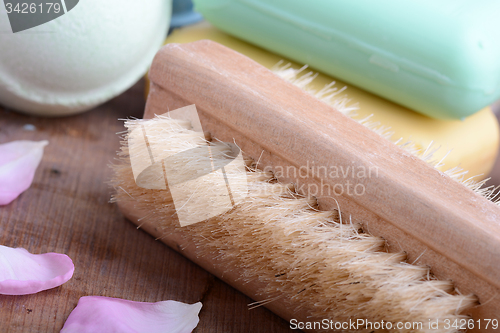 Image of soap, comb, sea salt, spa stones and flower petals on wooden table, close up