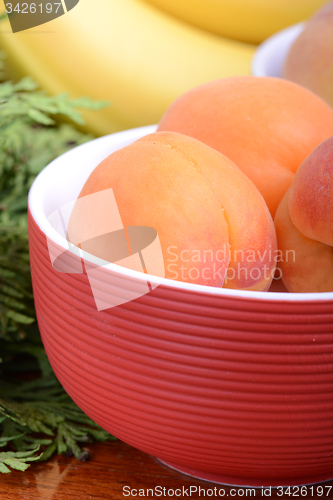 Image of bananas and apricots on red plate, close up