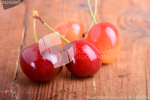 Image of wooden plate with dark red juicy cherries close up