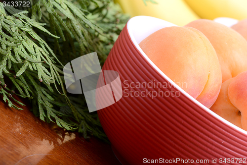 Image of bananas and apricots on red plate, close up