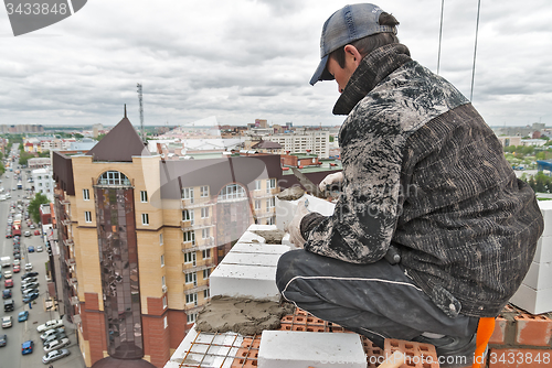 Image of Bricklayer on construction over street traffic