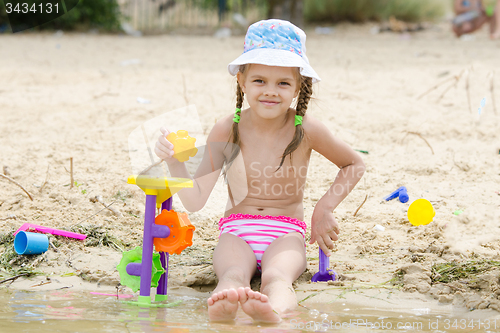 Image of Five-year girl playing on the river sand