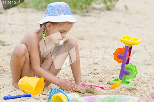 Image of Five-year girl on the river playing in the sand