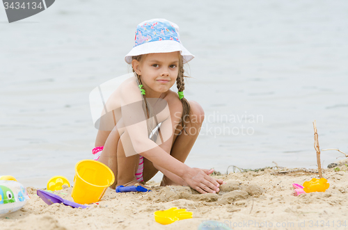 Image of Five-year girl on the beach playing in the sand
