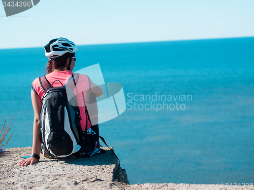 Image of Woman sitting om rock over sea landscape