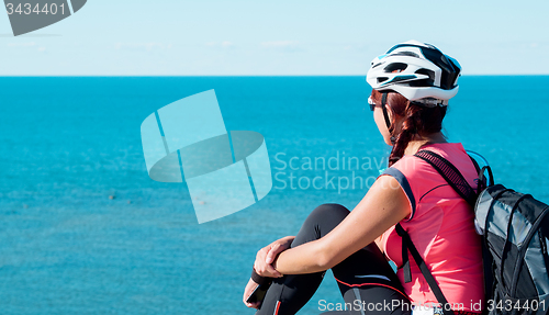 Image of Woman sitting om rock over sea landscape