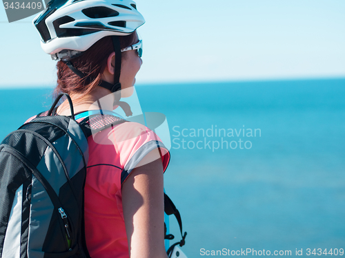 Image of Woman sitting om rock over sea landscape