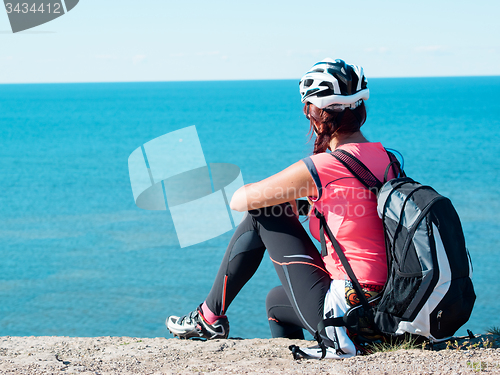 Image of Woman sitting om rock over sea landscape