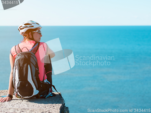 Image of Woman sitting om rock over sea landscape