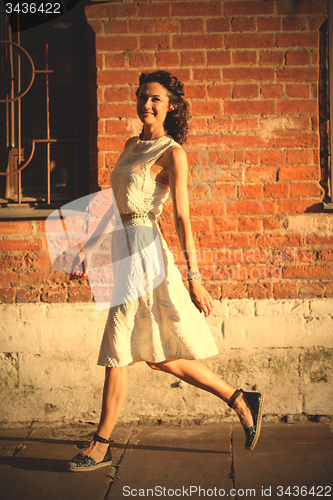 Image of pretty tanned middle-aged woman in a white dress