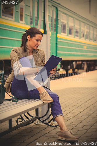 Image of beautiful woman traveler taking notes in a notebook