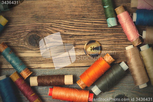 Image of one vintage button and coils of colored threads