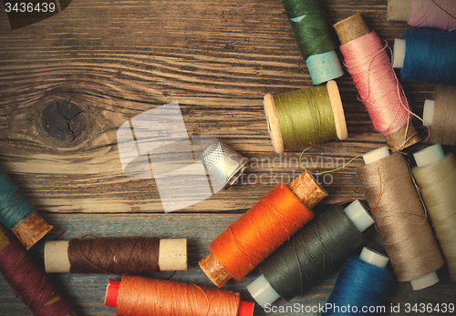 Image of thimble and spools of thread on an aged wooden surface