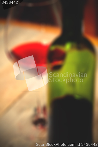 Image of red wine in glass and green bottle