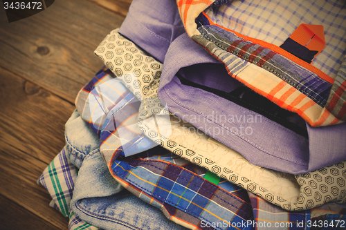 Image of stack of colored cotton shirts on a wooden shelf