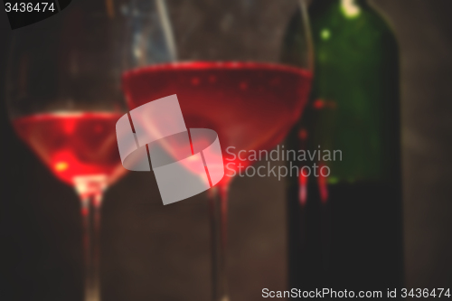 Image of red wine in two goblets and green bottle