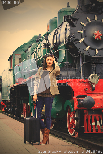 Image of woman traveler with luggage near retro puffer
