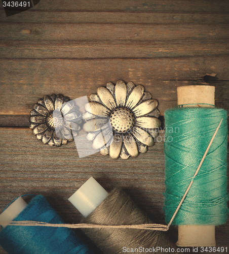 Image of two vintage buttons flowers and spools with threads