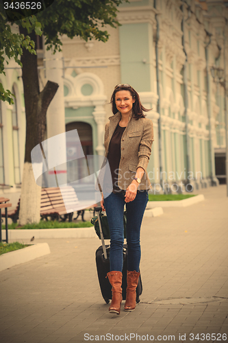 Image of pretty adult woman with a suitcase walking on the apron landside