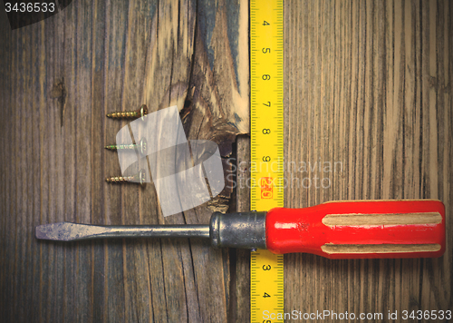Image of old screwdriver, three screws and measuring tape 