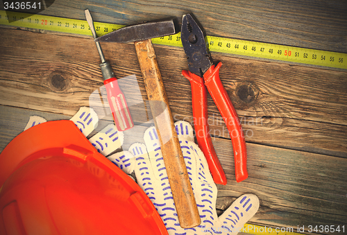 Image of Vintage pliers, hammer, screwdriver, tape measure, a bright helm