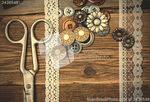 Image of antique lace, button and a tailor scissors