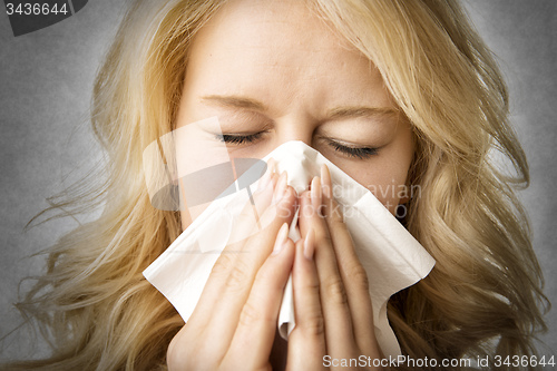 Image of Ill woman with tissue is sneezing