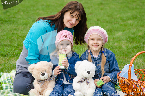 Image of Mum embraces daughters on a picnic