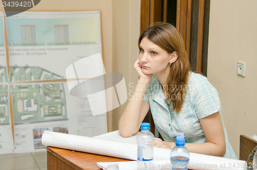 Image of Sad student sitting at desk with drawings