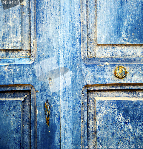 Image of dirty stripped paint in the blue wood door and rusty nail