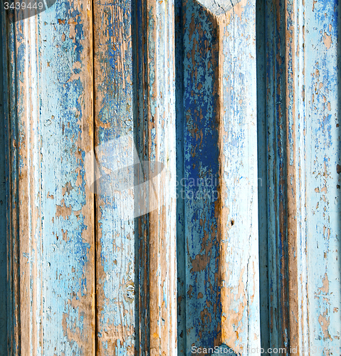 Image of dirty stripped paint in the blue wood door and rusty nail