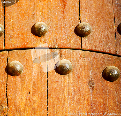 Image of metal nail dirty stripped paint in the brown   red wood door and