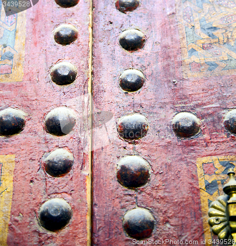 Image of nail dirty stripped paint in the brown wood door and rusty yello