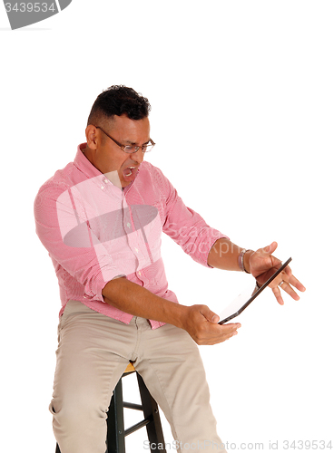 Image of Man screaming at his tablet computer.