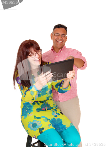 Image of A middle age couple having fun with the tablet.