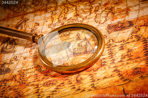 Image of Vintage magnifying glass lies on an ancient world map