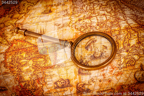 Image of Vintage magnifying glass lies on an ancient world map