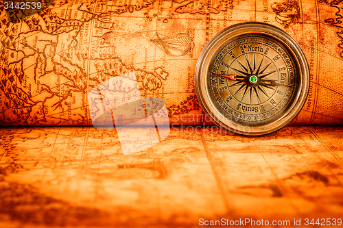 Image of Vintage compass lies on an ancient world map.