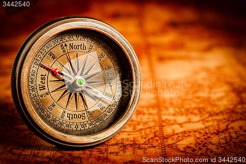 Image of Vintage compass lies on an ancient world map.