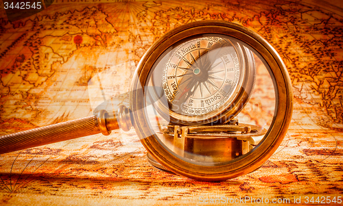 Image of Vintage magnifying glass lies on an ancient world map