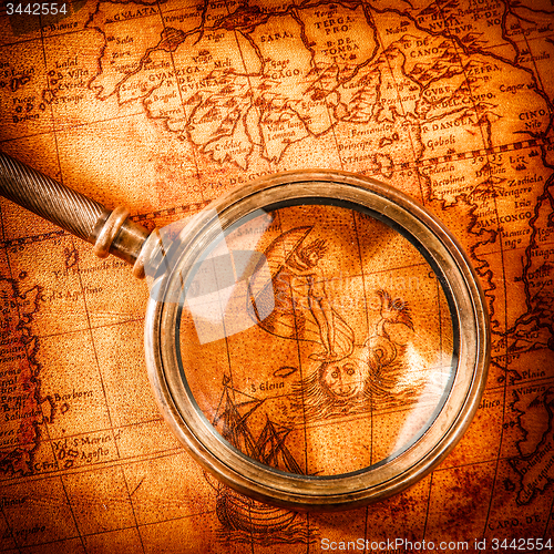 Image of Vintage magnifying glass lies on an ancient world map